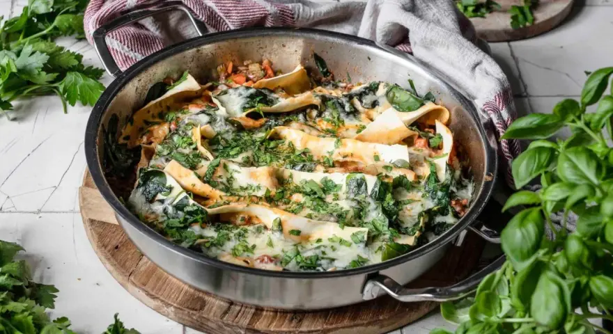 Lasagneplatten vorkochen ohne verkleben: Ein köstliches Gericht mit Spinat und Käse in einer Pfanne, garniert mit frischen Kräutern.