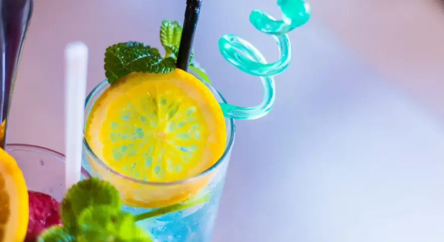 Orzeźwiający drink z sokiem żurawinowym, ozdobiony plasterkiem cytryny i listkami mięty. Idealny na upalne dni.
