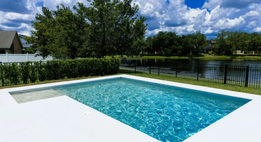 Agua de piscina blanquecina, cristalina y refrescante, con reflejos del cielo azul y nubes blancas. Un oasis de paz.