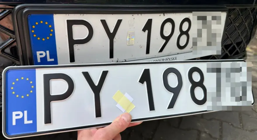 Dwie polskie tablice rejestracyjne PY 198. Jedna jest zamontowana na samochodzie, druga trzymana w ręku.