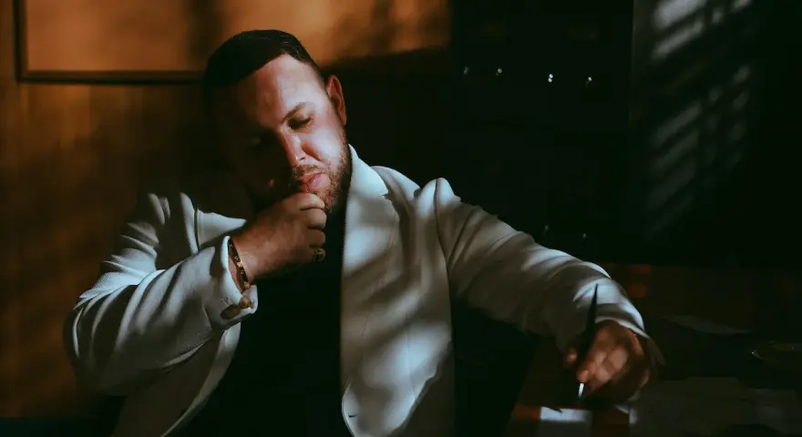 Louis Villain, w wieku około 40 lat, w białej marynarce, zamyślony przy biurku.