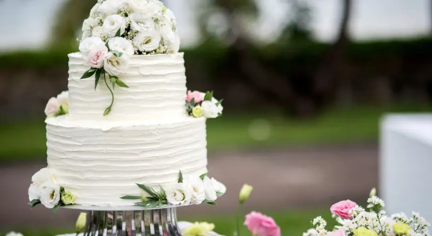 Elegancki, dwupiętrowy tort weselny ozdobiony bukietem białych i różowych, **jakie żywe kwiaty na tort** dodają mu uroku.
