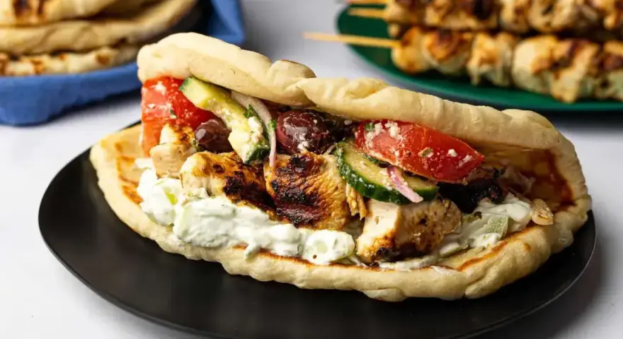 En saftig gyros med grillspett, tzatziki, tomat, gurka och oliver i pitabröd. Perfekt för ett snabbt grillspett recept.