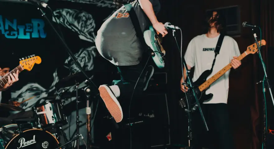 Ein Gitarrist springt auf der Bühne, während ein Bassist spielt. Das ist Rockmusik in Aktion!
