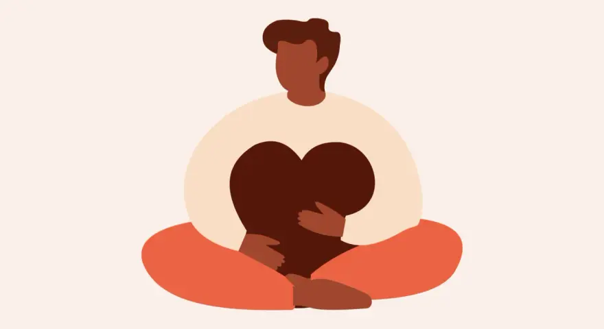 En person sitter i meditationsställning och håller ett hjärta. Detta illustrerar vad betyder mindfulness – att vara närvarande och omfamna sina känslor.