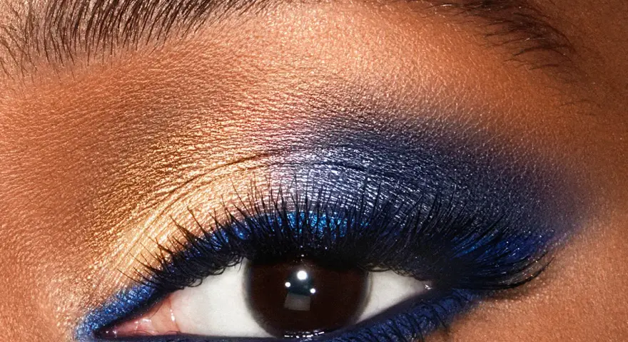 Un œil aux smoky eyes bleus intenses, rehaussé de fard doré et de paillettes. Un regard captivant.