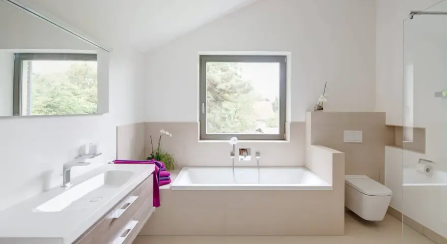 Salle de bain moderne avec baignoire, lavabo, douche vitrée et toilette suspendue.