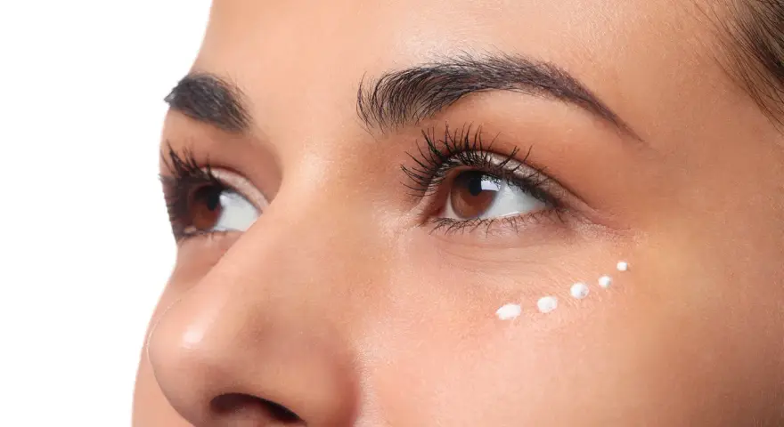 Application de crème hydratante sous les yeux, parfaite pour le maquillage hivernal.