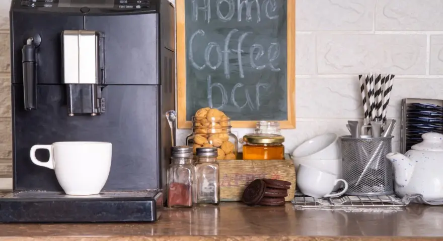 Máquina de café, taza, galletas y un letrero que dice "my Home Coffee bar". Todo listo para disfrutar de un momento de relax en tu zona de cafe en la cocina.