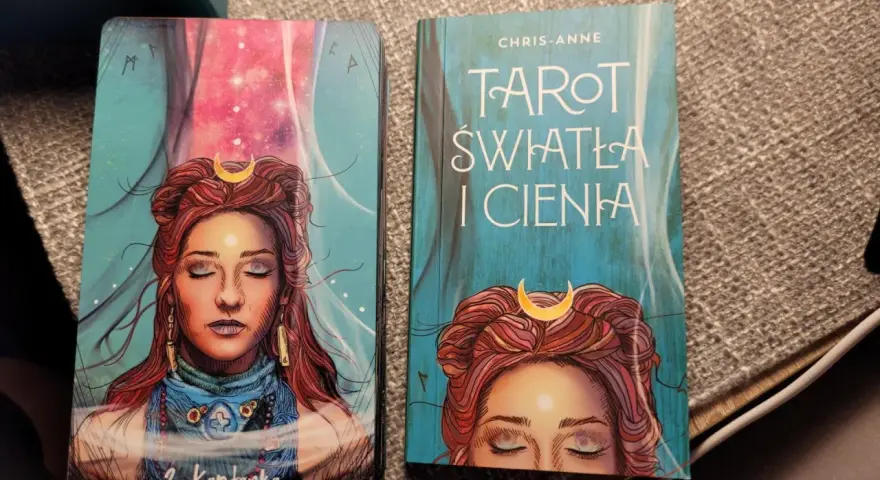 Karty i książka "Tarot Światła i Cienia" z wizerunkiem kobiety z księżycem na czole.