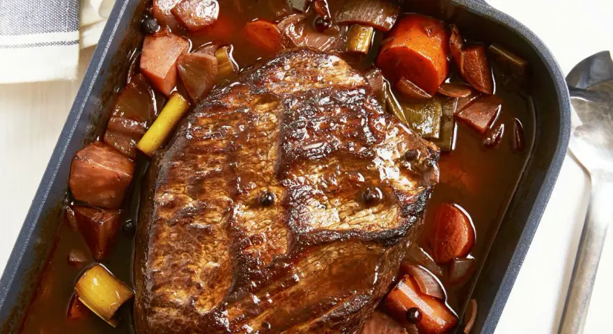 Herzhaftes Rinderbratenstück in dunkler Sauce mit Karotten und Lauch, perfekt für festliche Schmorgerichte an Weihnachten.