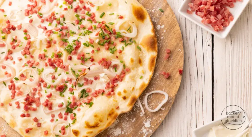 Flammkuchen vegetarisch mit Speckwürfeln, Zwiebelringen und Schnittlauch. Ein Genuss für jeden Gaumen!
