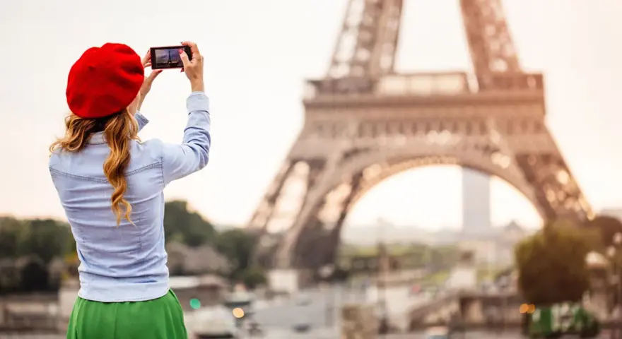 Mujer con boina roja toma foto de la Torre Eiffel. ¡Ideas de qué ver en París!
