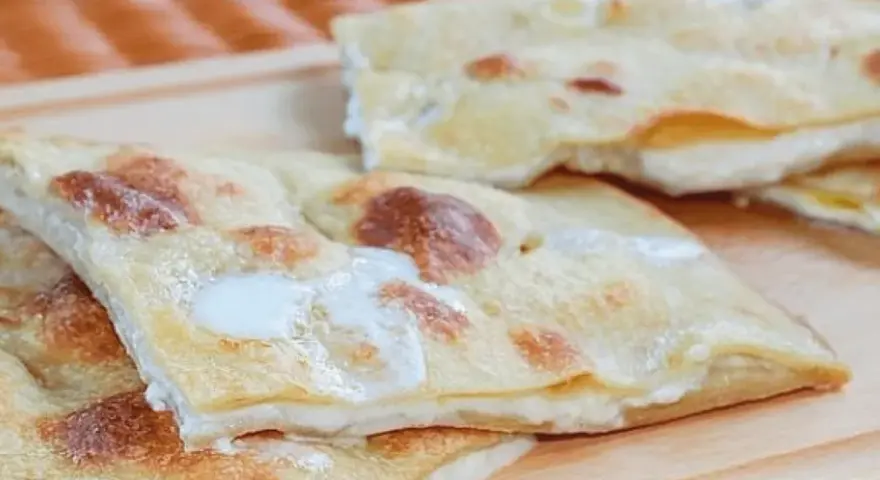 Focaccia di Recco, sottile e dorata, con il suo ripieno filante di formaggio fresco.