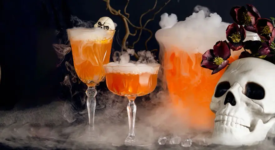 Två orangea drinkar med skum och en dödskalle, perfekt för en kuslig halloween-kväll.