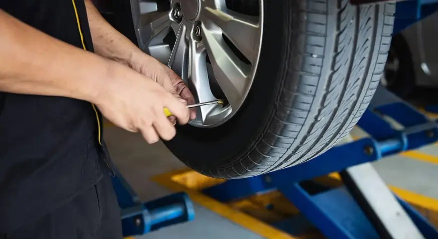 Mechanik sprawdza ciśnienie w oponie. To część usług wulkanizacji, czyli serwisu opon.
