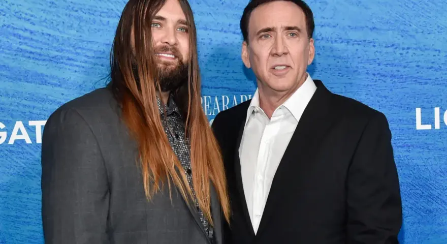 Weston Coppola Cage z długimi włosami i Nicolas Cage na niebieskim tle.