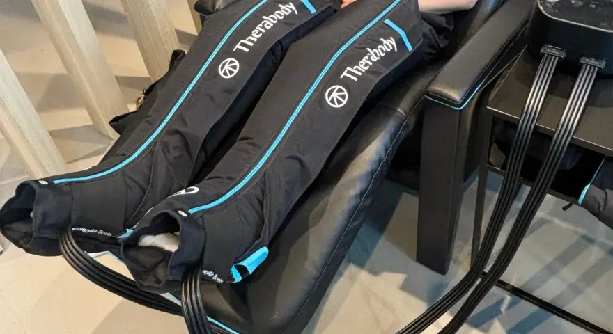 Are leg compression massagers good for you? This image shows a person using Therabody recovery boots, which are leg compression massagers, for a relaxing massage.