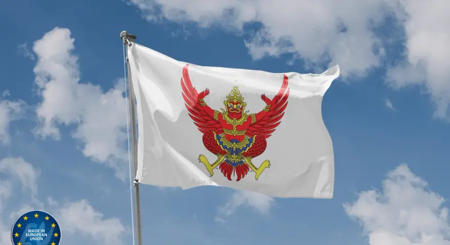 Biała flaga z wizerunkiem czerwonego Garudy, symbolu Tajlandii, powiewa na tle błękitnego nieba z chmurami.