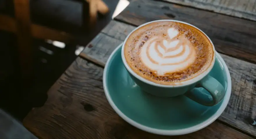 Aromaticzna kawa ristretto z pianką latte art na drewnianym blacie. Idealny poranek.