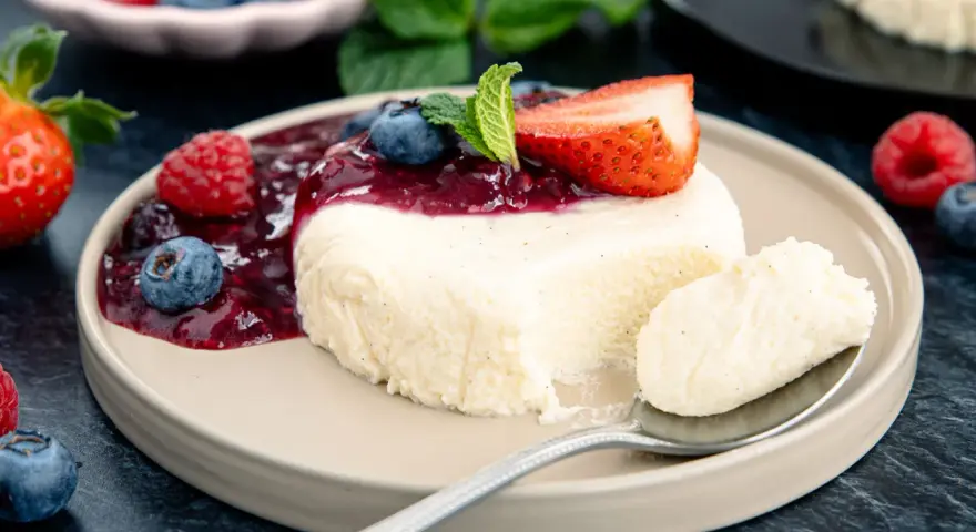 Cremige bayrische Creme mit Beerensoße, Erdbeere und Minze. Ein Löffel voller Genuss.