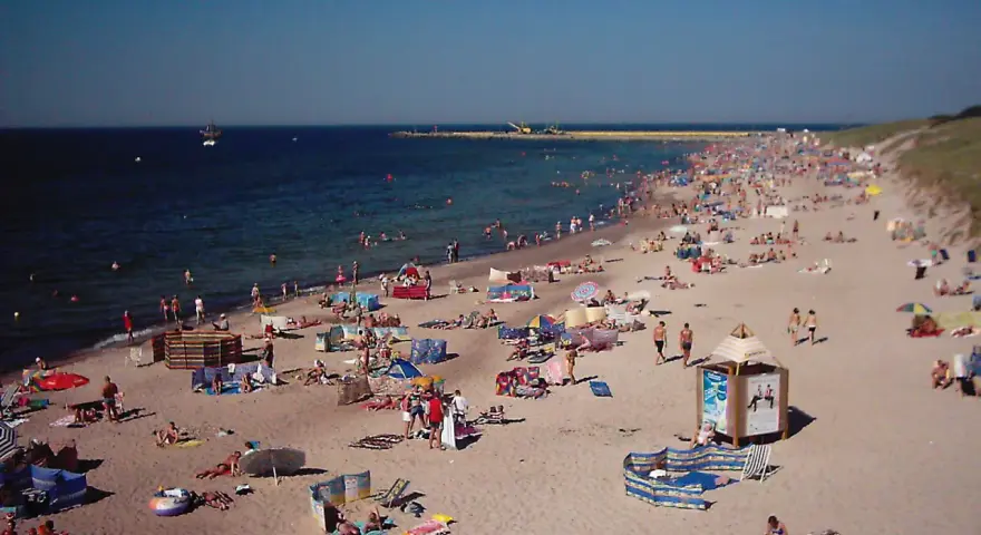 Tłum plażowiczów na piaszczystej plaży, woda i niebo. Czy to Darłówko wschodnie czy zachodnie?