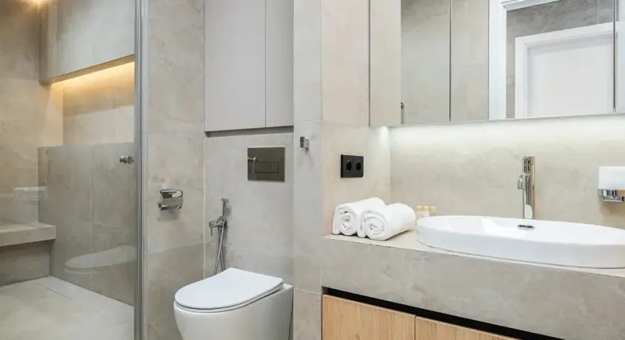 Modernt kaklat badrum med dusch, toalett och handfat. Ljus och stilren design.
