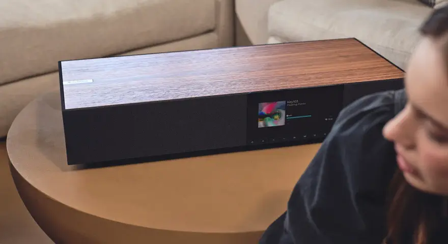 Elegancki Cambridge Audio One z drewnianym blatem i ekranem odtwarza muzykę.