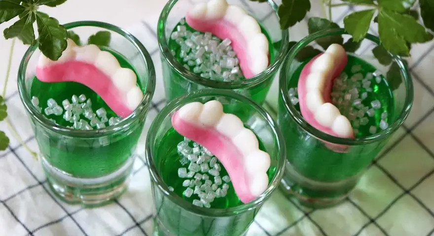 Gröna jello shots med godiständer och strössel. Perfekt för en festlig stämning!