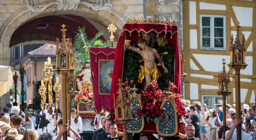 Prozession mit Jesus-Figur und Blumen. Fronleichnam ist ein gesetzlicher Feiertag, an dem solche Umzüge stattfinden.