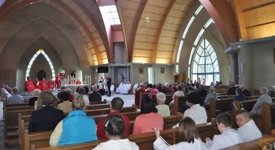 Nabożeństwo w kościele św. Jakuba w Łebie. Wierni siedzą w ławkach, a przy ołtarzu odprawiana jest msza.