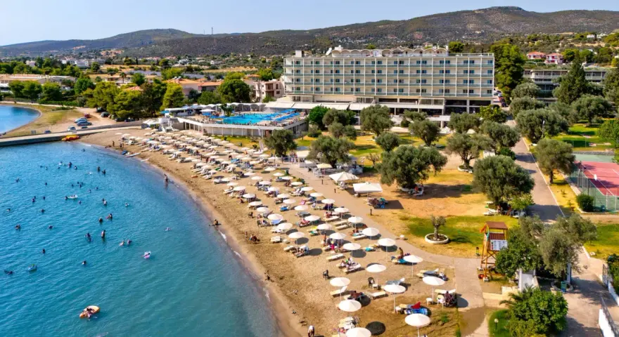 Piękna plaża na Evii, idealna na wycieczki fakultatywne. Hotel, basen, leżaki i mnóstwo ludzi kąpiących się w morzu.