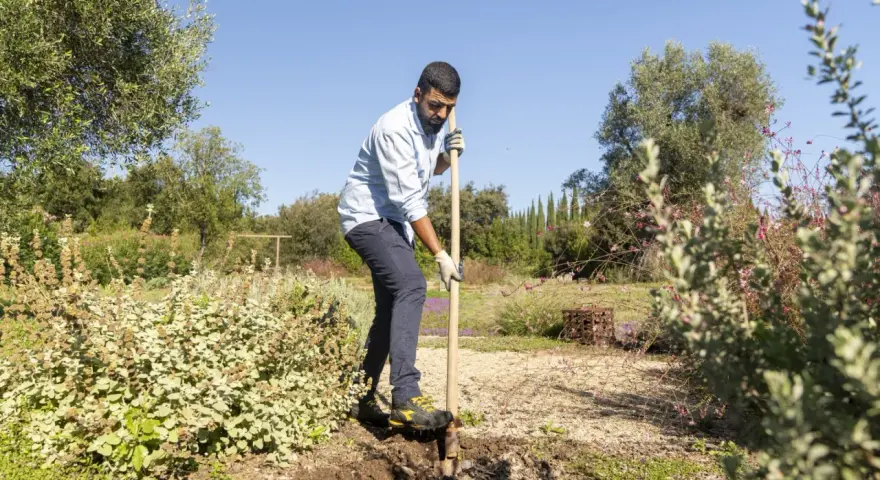 Uomo con pala in un giardino, forse per preparare il terreno con greenex nf dosaggio.