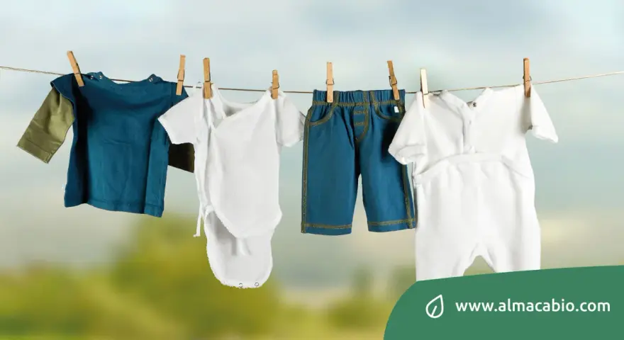 Baby clothes hanging on a clothesline: a blue long-sleeve shirt, a white onesie, blue shorts, and a white romper.