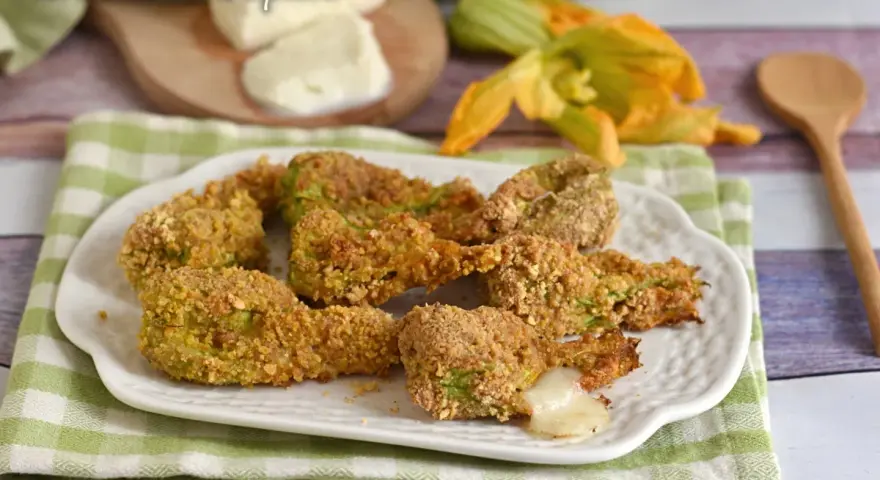 Fiori di zucca ripieni al forno, dorati e croccanti, con un cuore filante di mozzarella.