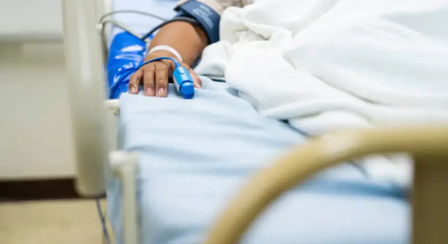 Paciente en cama de hospital con oxímetro en el dedo, indicando la necesidad de permiso por enfermedad.