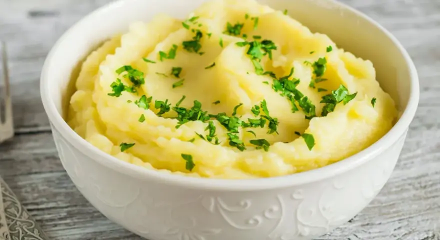 Puszyste, kremowe puree ziemniaczane, posypane świeżą natką pietruszki. Idealny dodatek do obiadu, który pokazuje, jak zrobić puree.