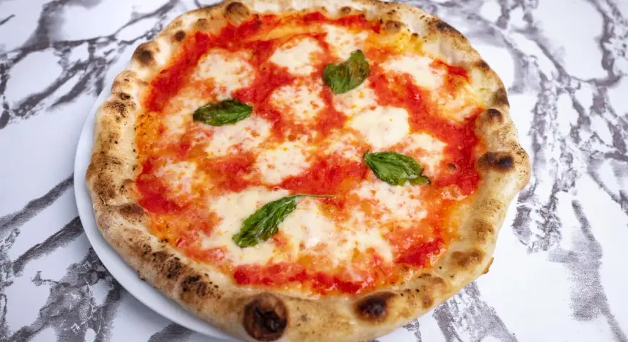 Pyszne ciasto na pizzę neapolitańską z pomidorami, mozzarellą i bazylią, idealne na letni wieczór.