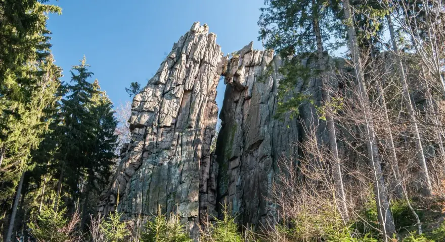 Skalny most na rudawych janowickich szlakach, otoczony drzewami.