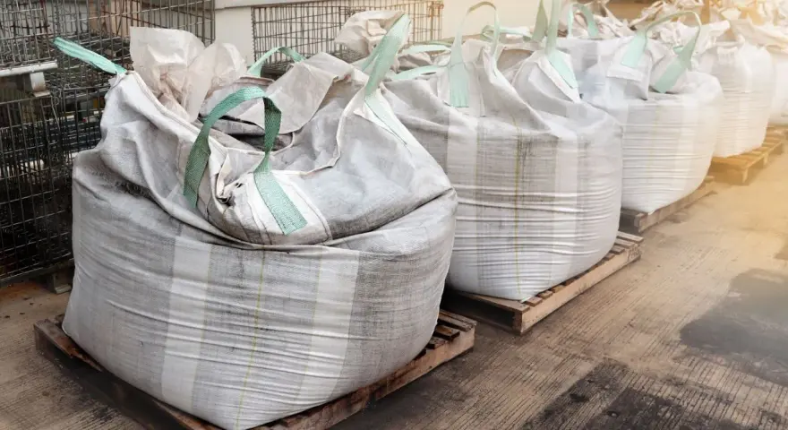 Rząd dużych worków big bag, każdy o pojemności ok. 1 m3, ustawionych na paletach.