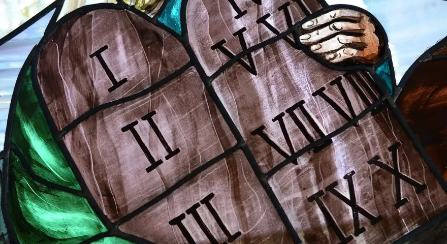 Witraż przedstawia kamienne tablice z wyrytymi cyframi rzymskimi, symbolizujące dekalog przykazania. Widoczne są cyfry I, II, III, IV, V, VI, VII, VIII, IX, X.