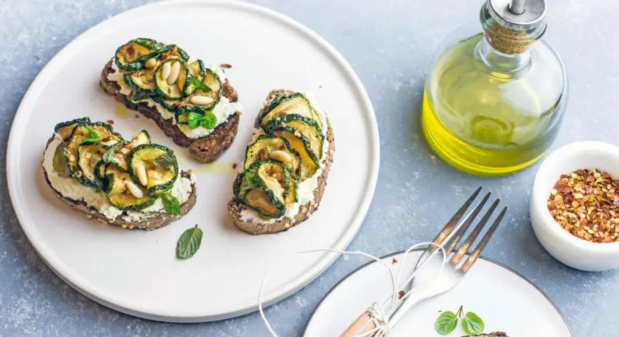 Bruschetta con zucchine grigliate, ricotta e pinoli, condita con un filo d'olio.