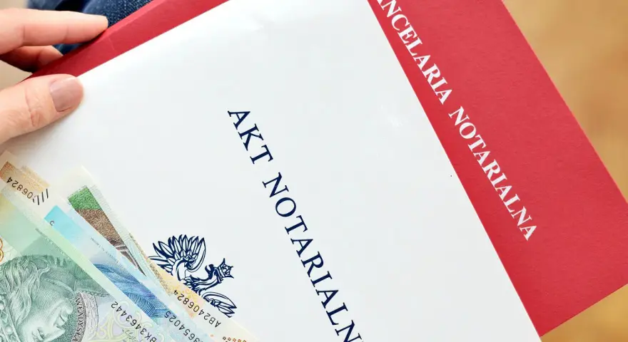 Akt notarialny i polskie banknoty w dłoni.