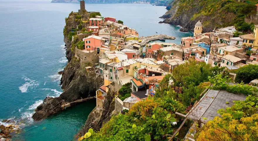Kolorowe domy Cinque Terre na klifie, idealne na wakacyjne loty do Włoch.