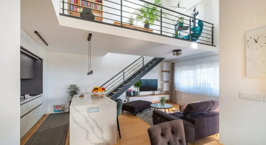 Soggiorno moderno con soppalco, libreria, cucina a isola e scala a vista. Ottime idee soppalco garage per sfruttare lo spazio.