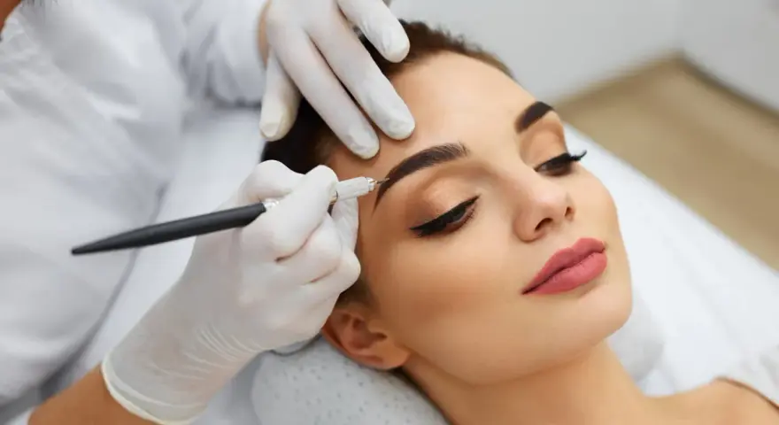 Une esthéticienne crée des sourcils brossés vers le haut sur une cliente, perfectionnant son regard avec précision.
