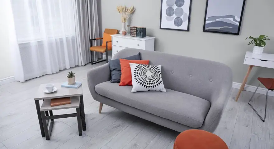 Przytulny salon z sofą i fotelami. Ciepły szary kolor ścian tworzy spokojną atmosferę.