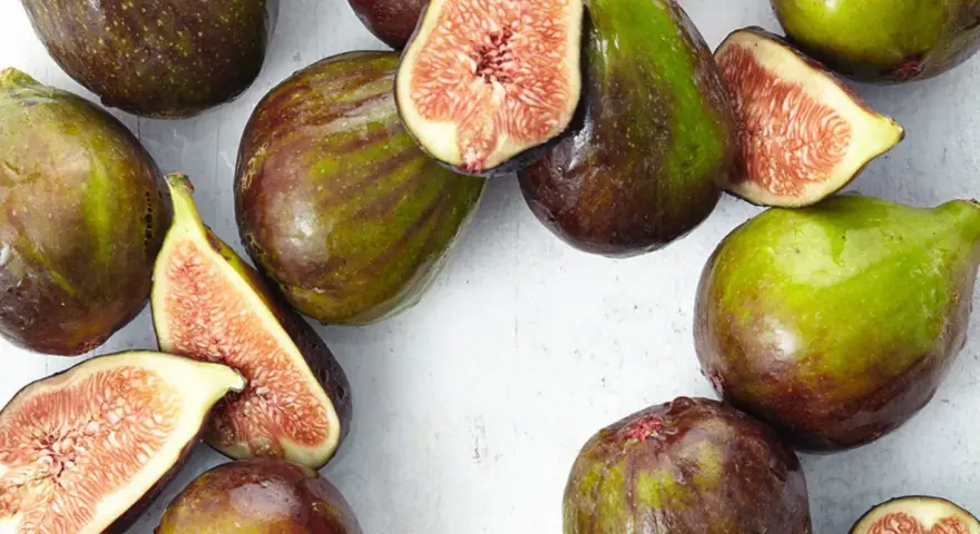 Frische Feigen, teils angeschnitten, zeigen ihr saftiges Inneres. Man fragt sich, wie schmecken feigen wohl? Süß und honigartig.