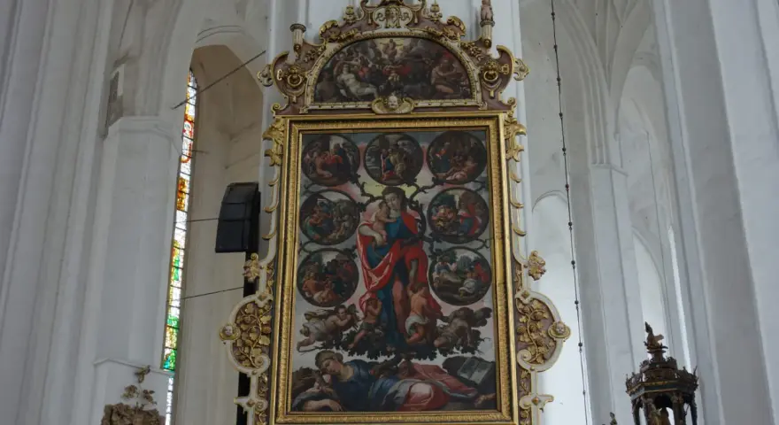 Wnętrze Bazyliki Mariackiej. Centralnie umieszczony, bogato zdobiony obraz przedstawia Matkę Boską z Dzieciątkiem i sceny z życia świętych.