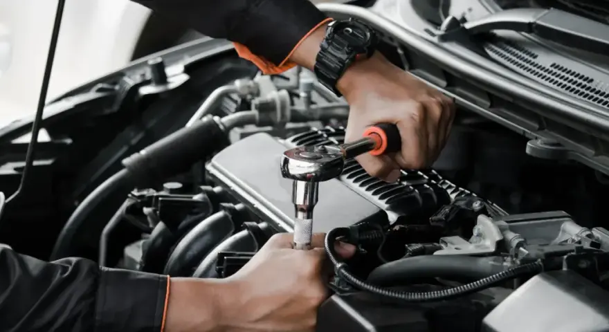 Mechanik wykonuje wymiana pompy paliwa krok po kroku, używając klucza nasadowego do odkręcenia śrub w silniku samochodu.